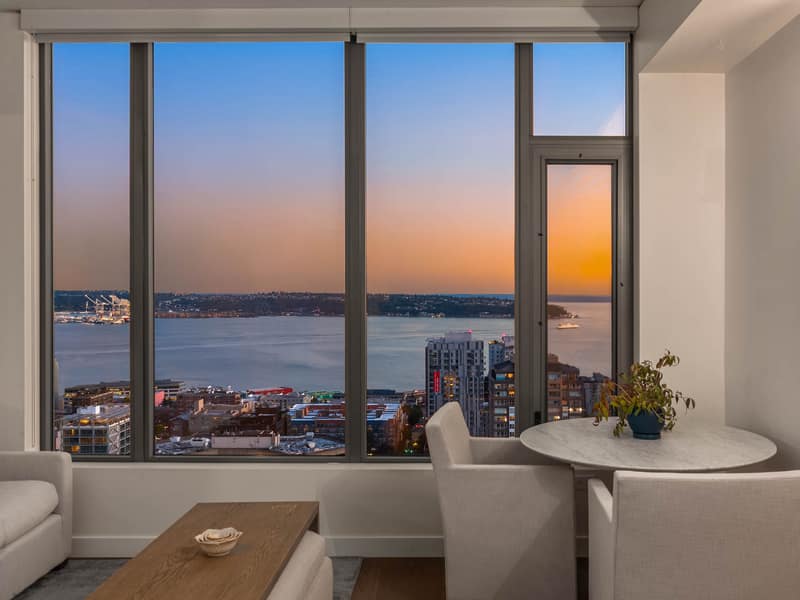 Living room window during dusk with city and water beyond